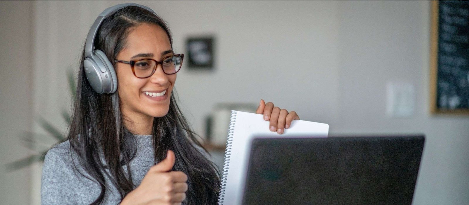 French Smiling woman attending French language lessons online, giving a thumbs up