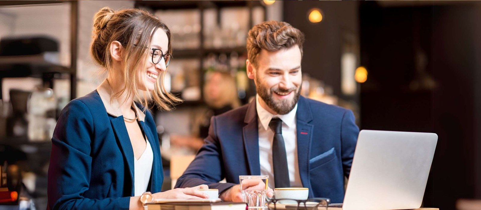 Two professionals collaborating on a laptop during professional-development-training in a modern café.