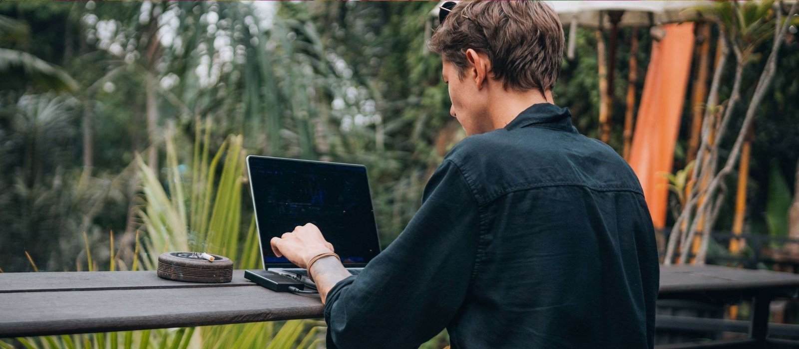 indonesia Man attending Indonesian classes online while working on a laptop in a tropical outdoor setting