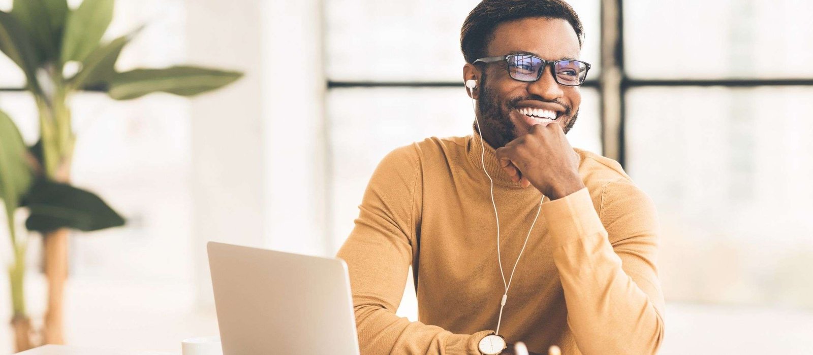 Smiling man attending Portuguese language classes online while sitting at a desk with a laptop